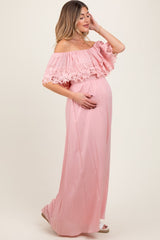 woman wearing a pink off-the-shoulder maternity gown with lace detail and a visible baby bump