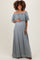 woman wearing a light gray off-the-shoulder maternity dress with lace detailing and holding her baby bump
