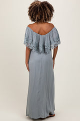 woman wearing a light blue off-the-shoulder maternity dress with lace details and a flowing silhouette, showing her back