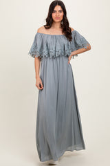 woman wearing a light blue off-the-shoulder maxi dress with lace detailing on the sleeves