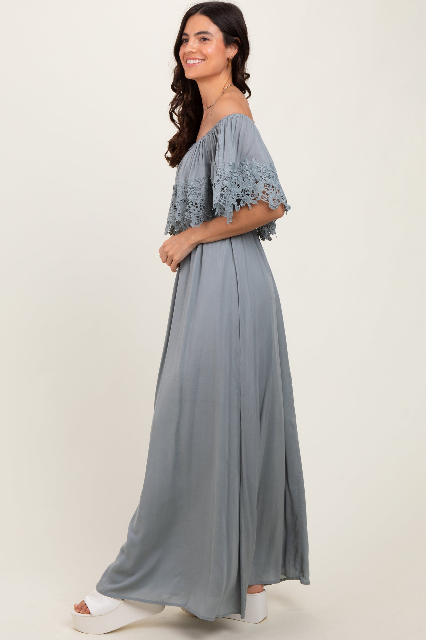 woman wearing a long gray off-shoulder maxi dress with lace details and flowing silhouette