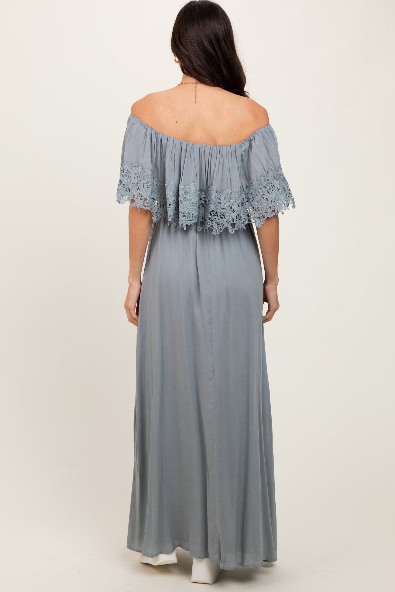 woman wearing a light gray off-the-shoulder maxi dress with lace details on the sleeves, shown from the back
