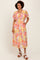 woman wearing a colorful floral midi dress with short sleeves and pockets, standing with hands in pockets