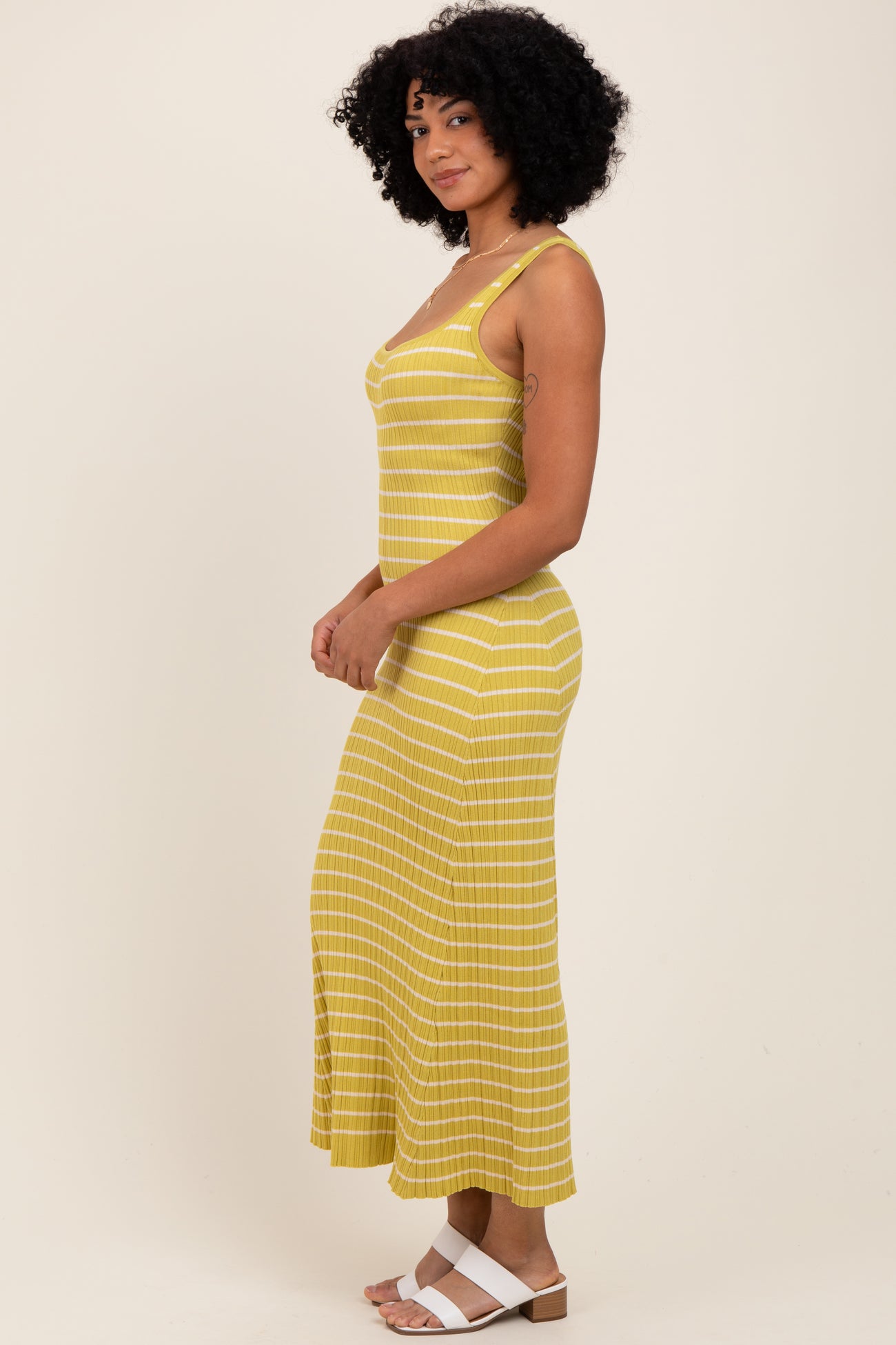 woman wearing a yellow striped maxi dress with spaghetti straps and a fitted silhouette