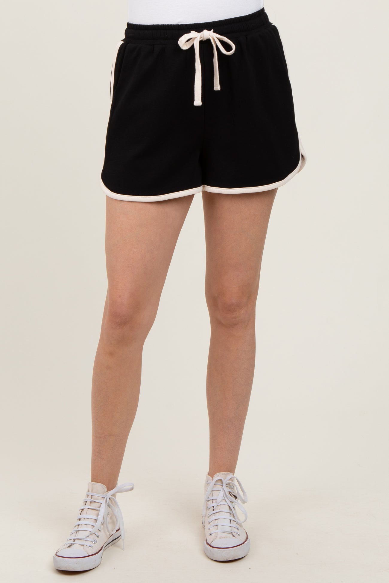woman wearing black athletic shorts with white trim and drawstring, paired with white sneakers