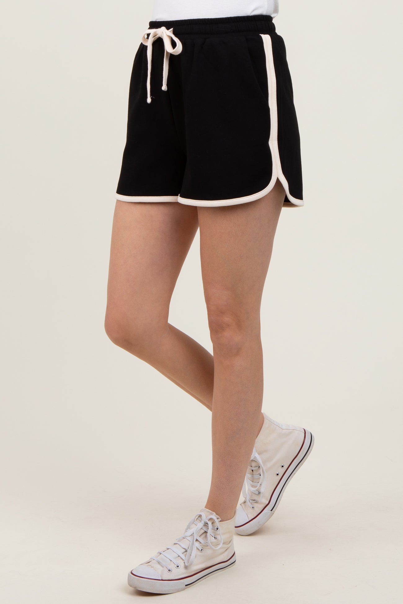 woman wearing black athletic shorts with white piping and a drawstring, paired with white sneakers