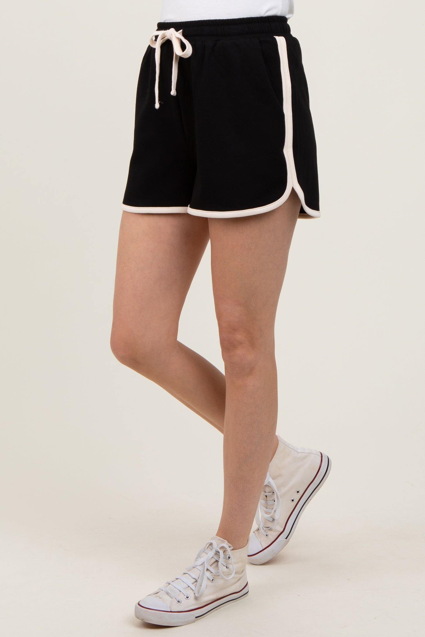 woman wearing black athletic shorts with white piping and a drawstring, paired with white sneakers