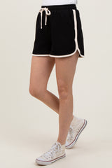 woman wearing black athletic shorts with white piping and a drawstring, paired with white sneakers