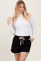 woman wearing a white long sleeve top and black drawstring shorts with white trim