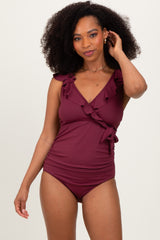woman wearing a burgundy ruffled one-piece swimsuit with a deep v-neck and tie waist detail