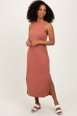 woman wearing a rust-colored sleeveless maxi dress with side slits and paired with white slide sandals