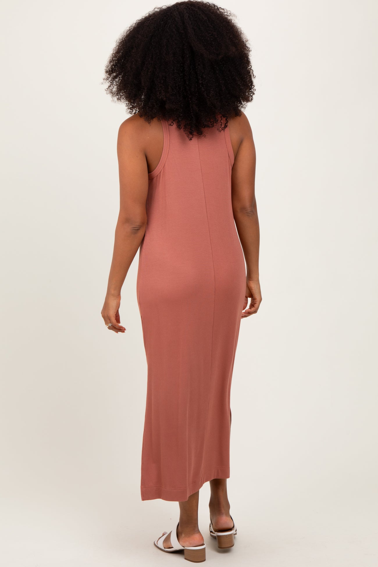 woman wearing a dusty rose sleeveless maxi dress with a fitted silhouette and a ribbed texture from the back
