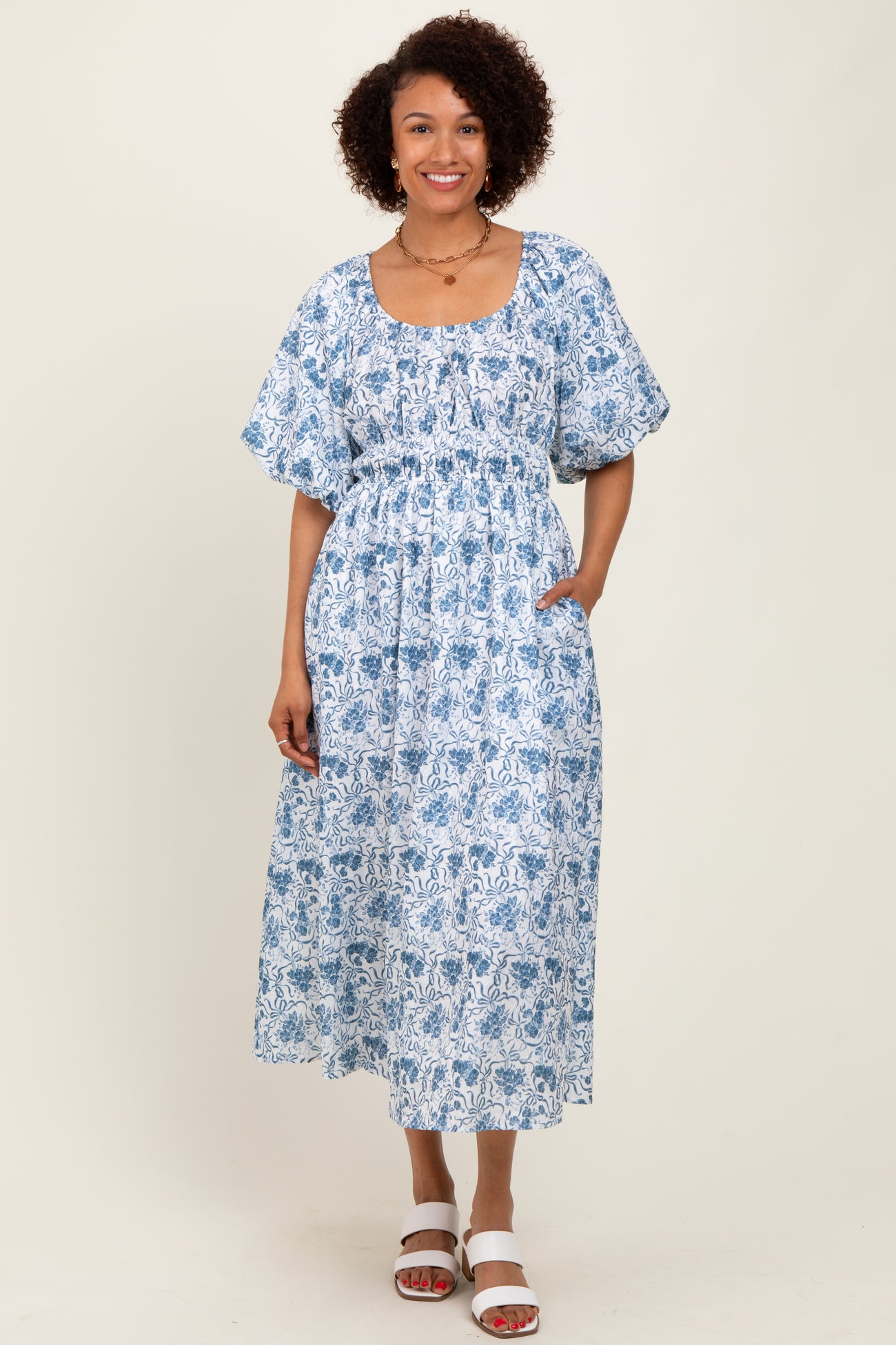 woman wearing a blue and white floral midi dress with puff sleeves and pockets
