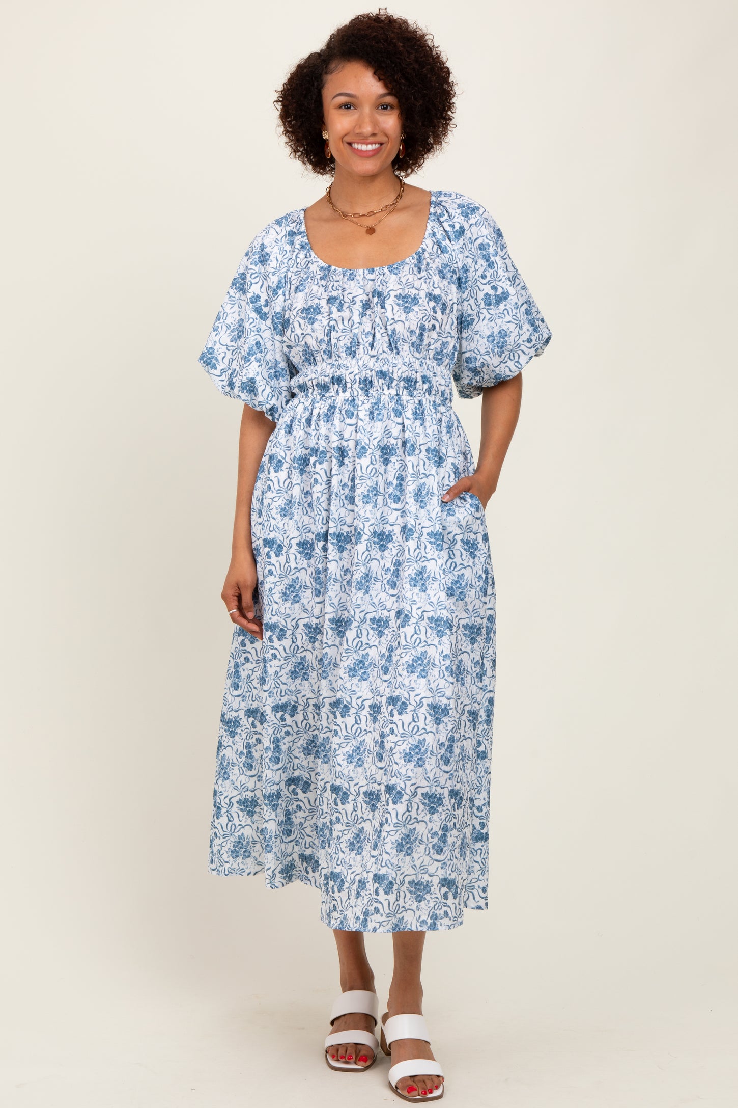 woman wearing a blue and white floral midi dress with puff sleeves and pockets
