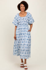 woman wearing a blue and white floral midi dress with puff sleeves and pockets
