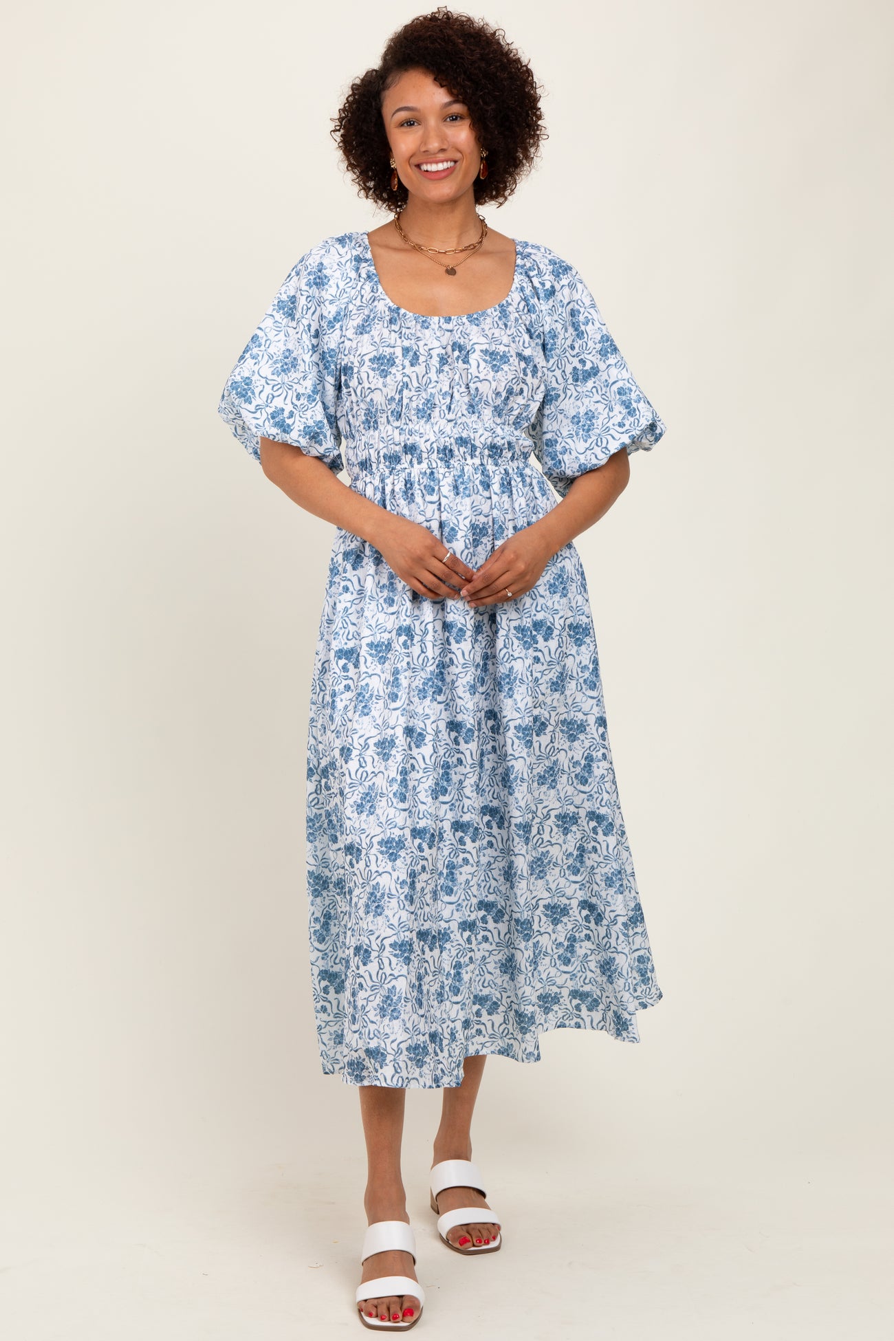 woman wearing a blue and white floral print midi dress with short puff sleeves and a square neckline