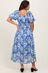 woman wearing a blue floral maternity maxi dress with puff sleeves and a smocked back