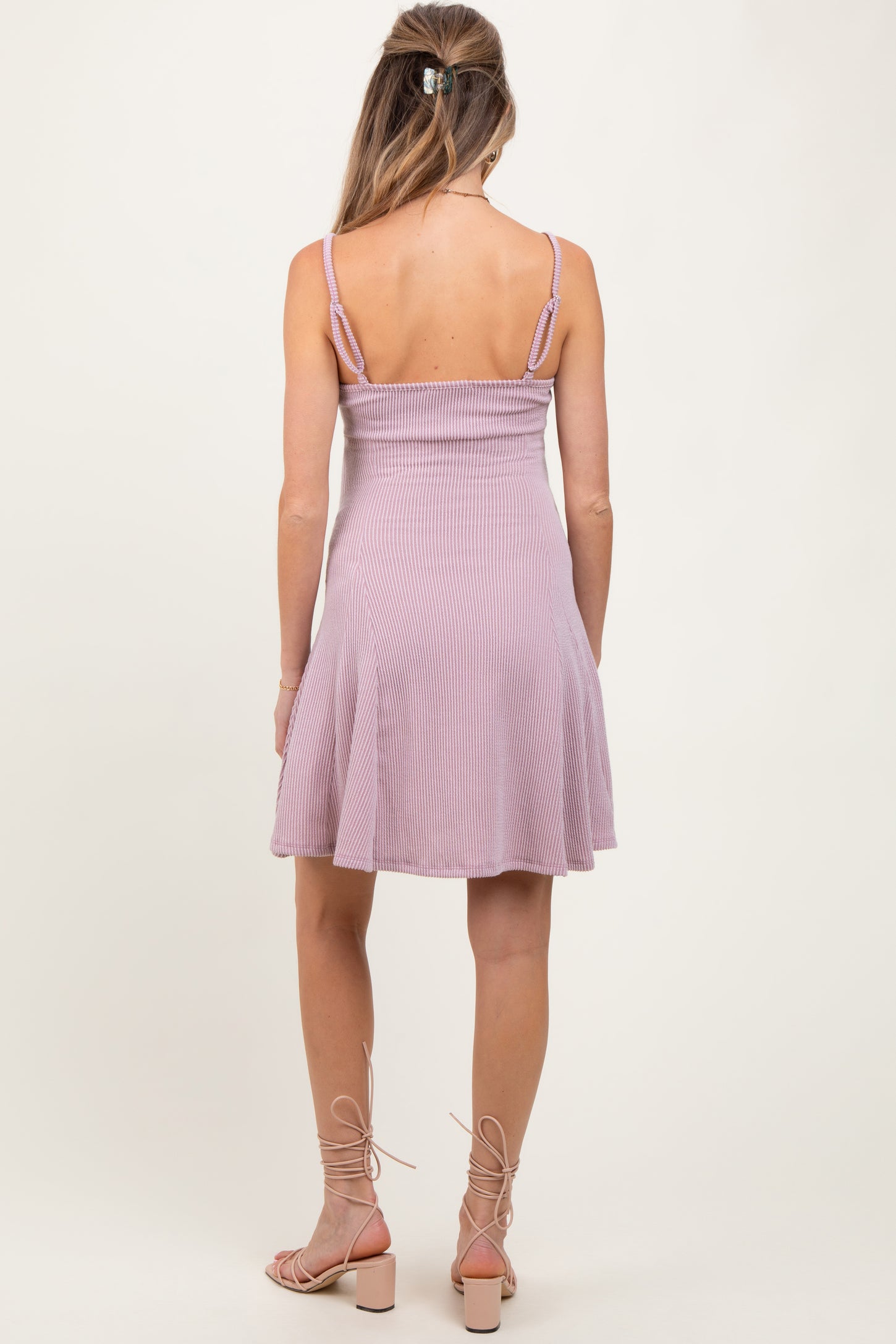 woman wearing a light purple ribbed maternity dress with adjustable straps and a flared skirt, seen from the back