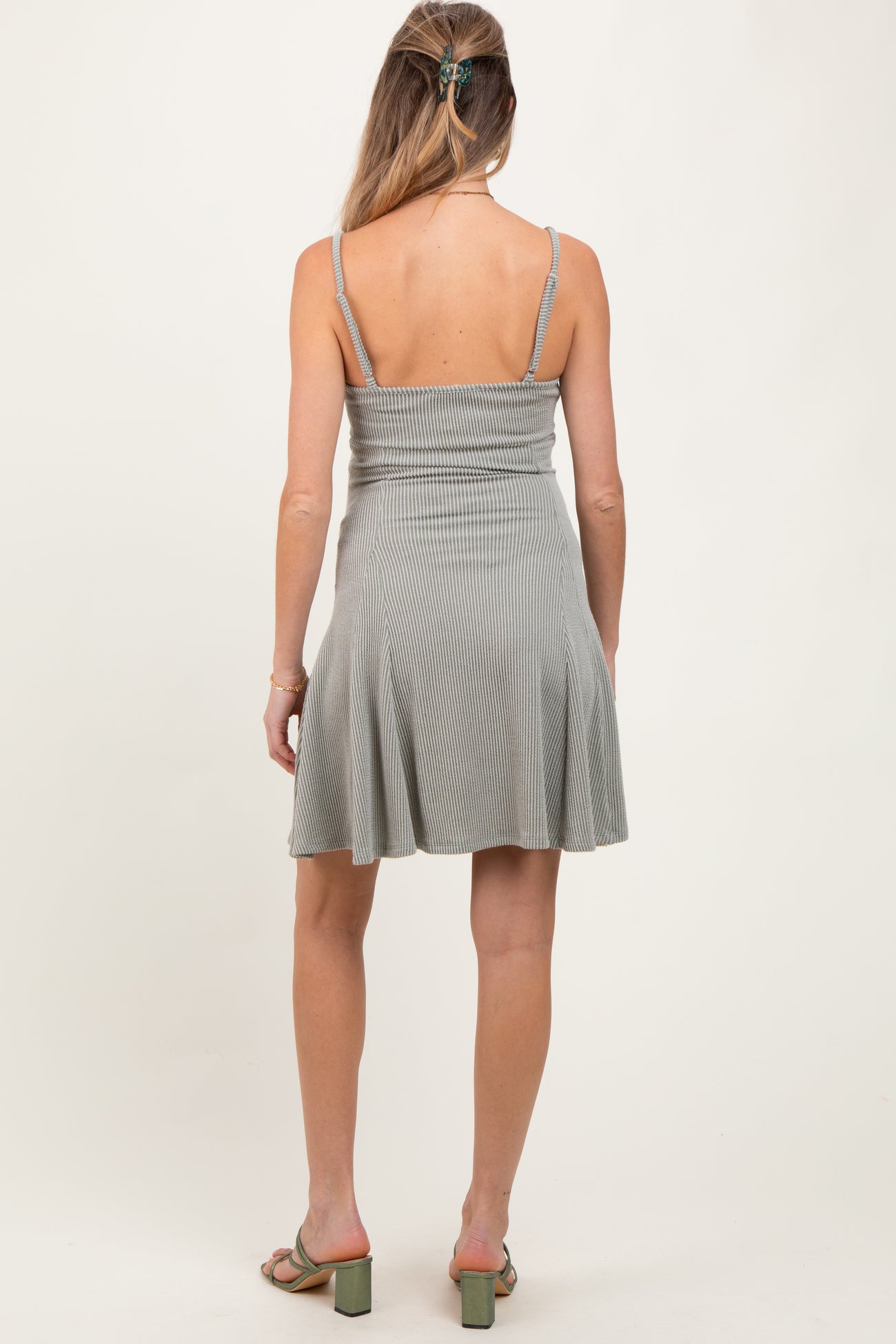 woman wearing a grey striped maternity dress with a flared skirt and adjustable spaghetti straps, showing her back