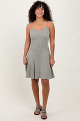 woman wearing a gray and white striped spaghetti strap skater dress with a flared skirt and black heeled sandals