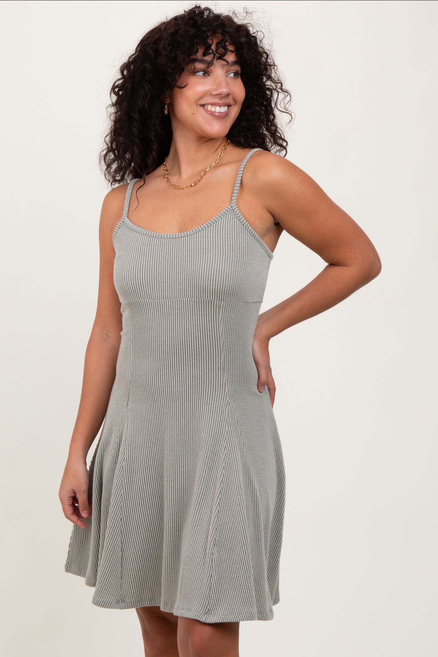 woman wearing a green and white striped spaghetti strap a-line dress with a flared skirt
