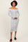 woman wearing a white and navy striped off-the-shoulder midi dress with long sleeves and button details