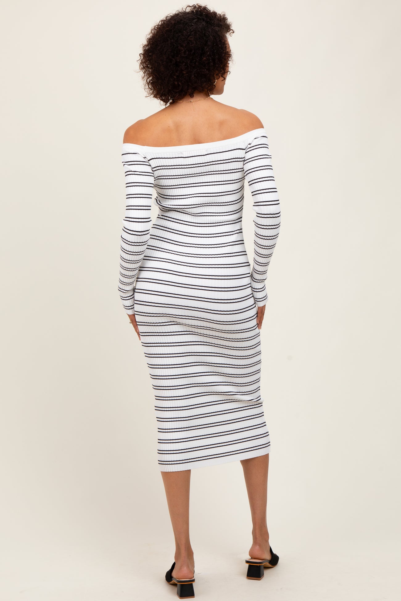 woman wearing a white and navy striped off-the-shoulder midi dress with long sleeves and a fitted silhouette