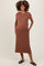 woman wearing a brown sleeveless maternity dress with pockets and a visible baby bump