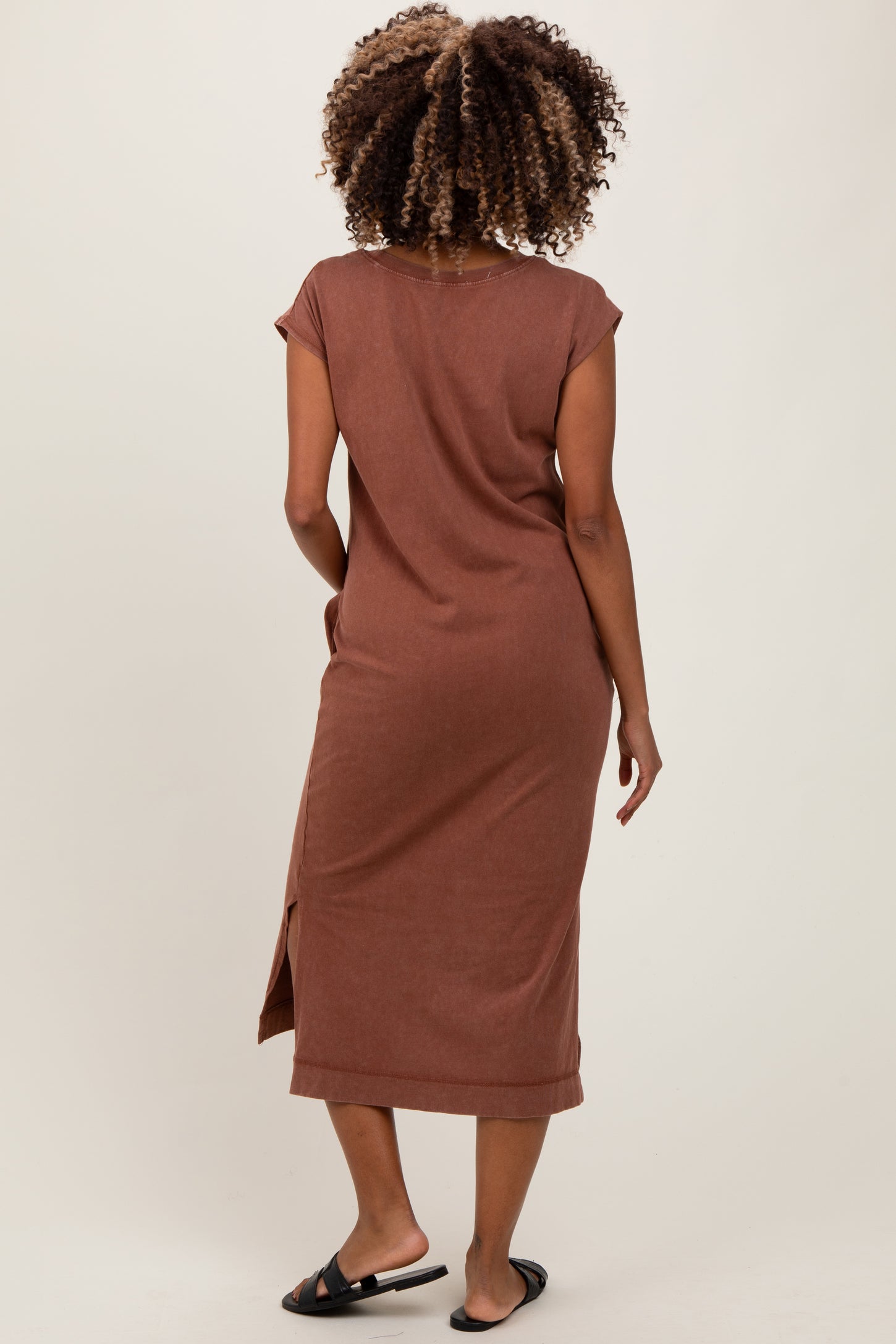 woman wearing a brown maternity maxi dress with short sleeves and a side slit, showing no visible baby bump
