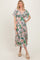 woman wearing a floral print maxi dress with short flutter sleeves and a tie front detail in a light pastel color