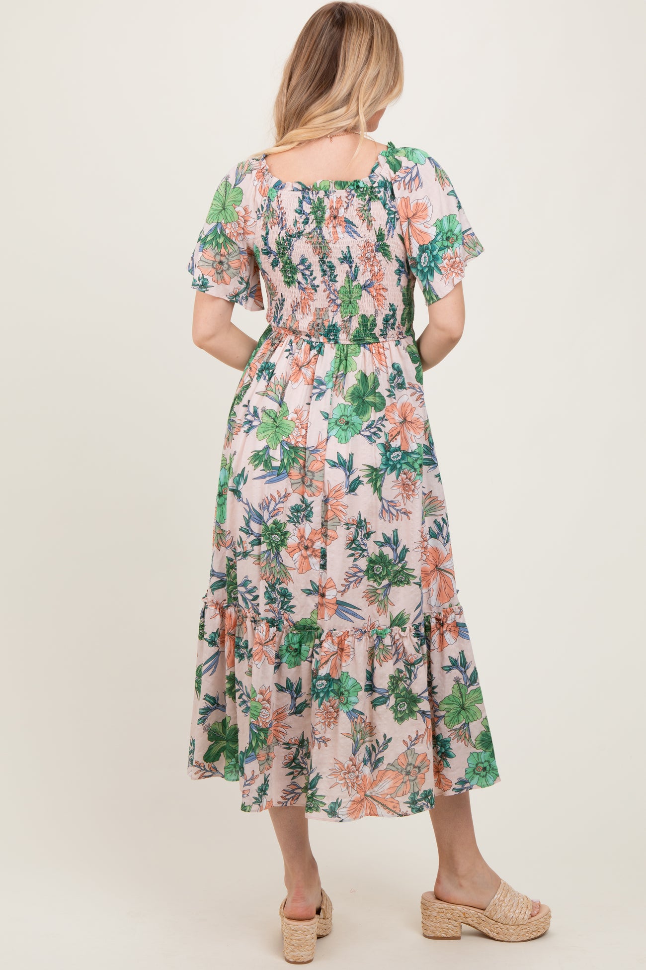 woman wearing a floral midi dress with short sleeves and smocked details, viewed from the back