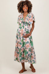 woman wearing a floral maternity maxi dress with short sleeves and a flowing skirt, holding her baby bump