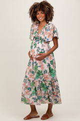 woman wearing a floral maternity maxi dress with flutter sleeves and holding her baby bump