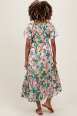 woman wearing a floral print maternity maxi dress with short flutter sleeves and a tiered skirt, showing her baby bump