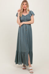 woman wearing a teal maxi dress with a smocked bodice, flutter sleeves, and a front button detail