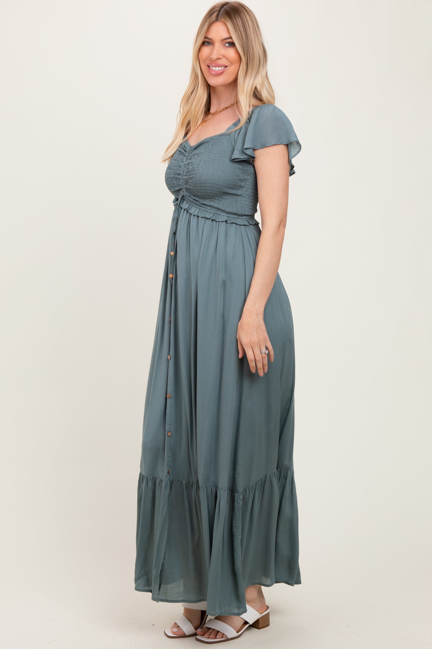woman wearing a teal maxi dress with short ruffle sleeves and a button-up front detail