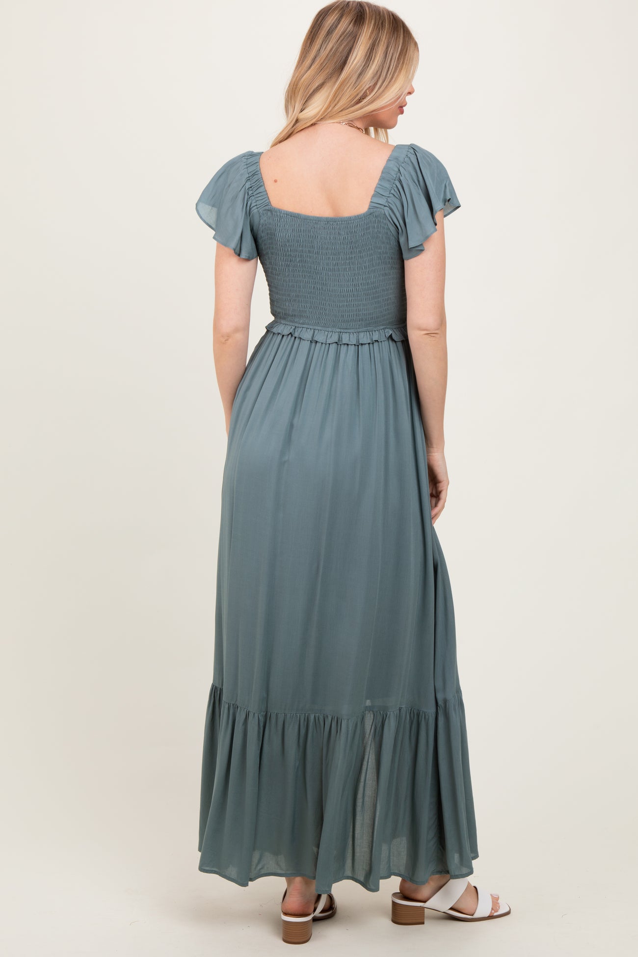 woman wearing a teal backless maxi dress with flutter sleeves and a smocked bodice