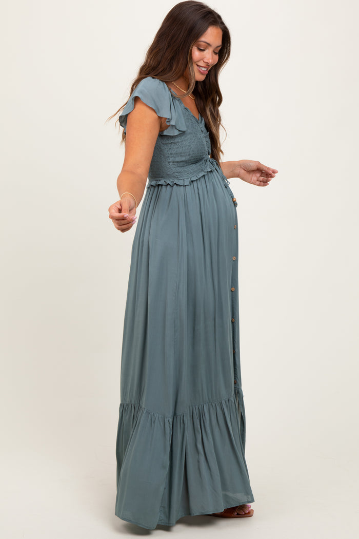 woman wearing a green maternity maxi dress with ruffle sleeves and a smocked bodice, showing her baby bump