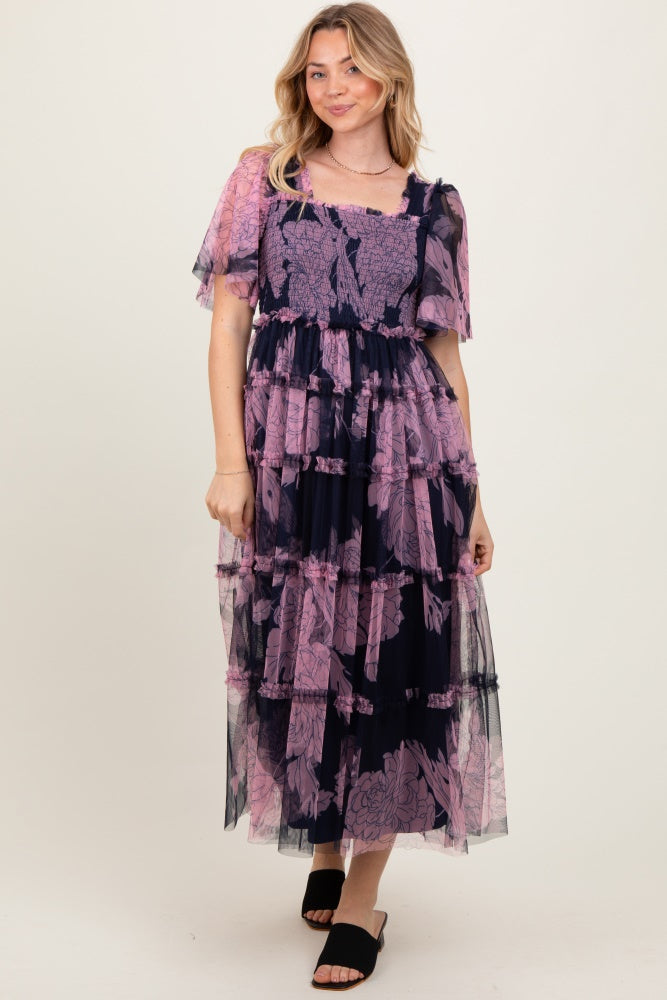 woman wearing a navy and pink floral tiered maxi dress with short sheer sleeves and a square neckline