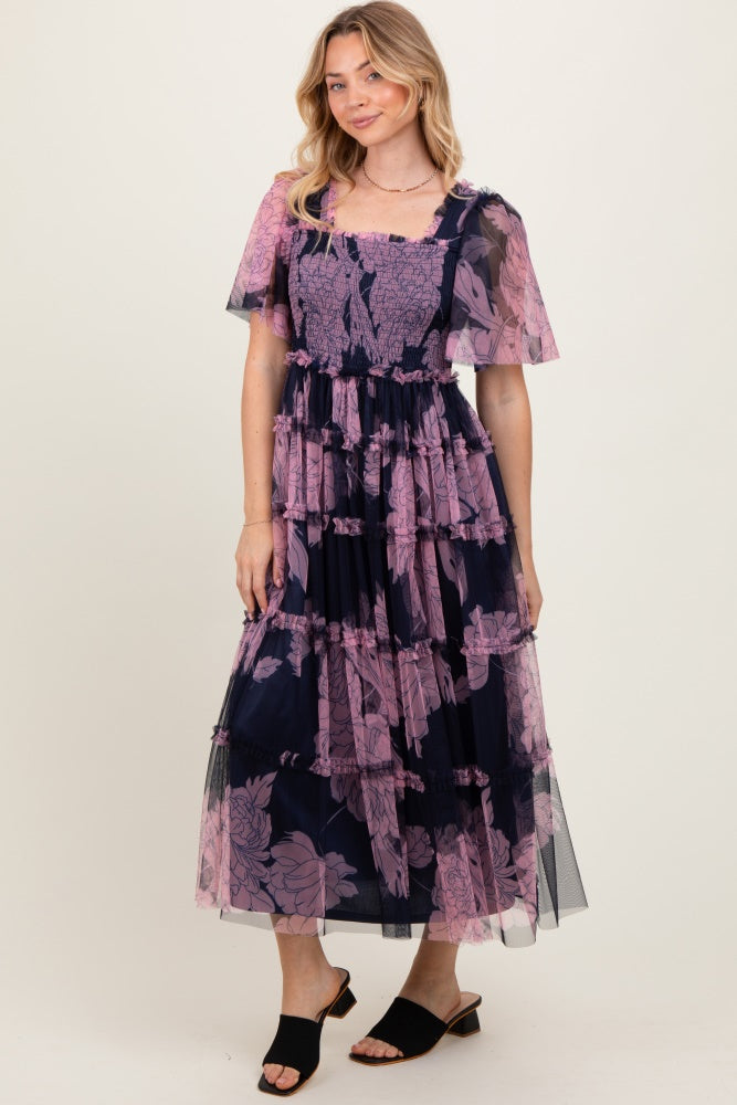 woman wearing a navy blue floral tiered maxi dress with short sheer sleeves and a square neckline