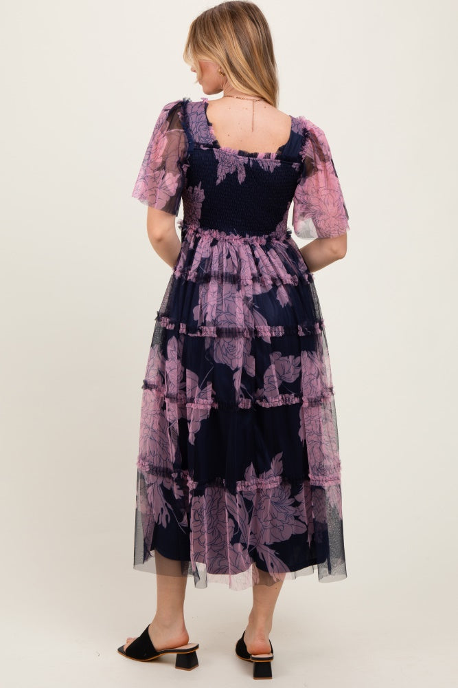 woman wearing a navy blue floral tiered maxi dress with short sleeves and smocked bodice, shown from the back