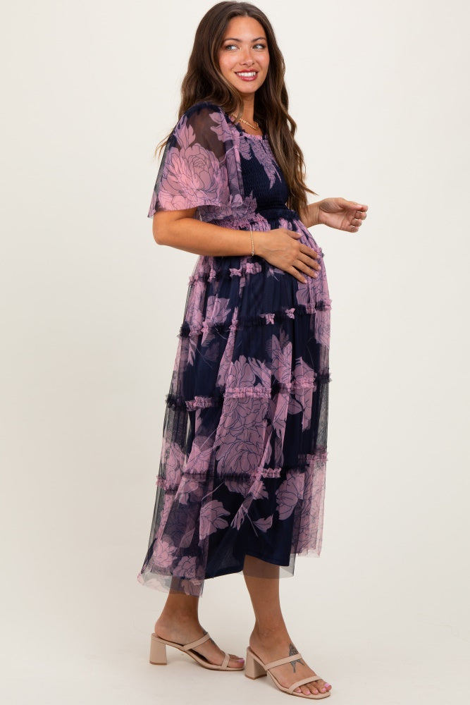 woman wearing a navy blue floral maternity dress with layered tulle and a visible baby bump