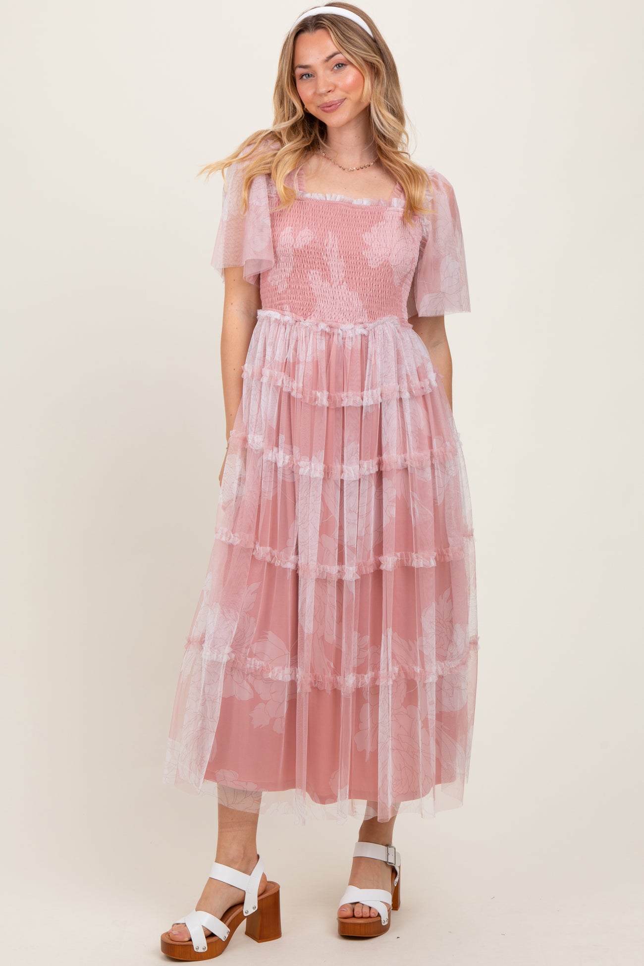 woman wearing a light pink tiered lace dress with short puff sleeves and a square neckline