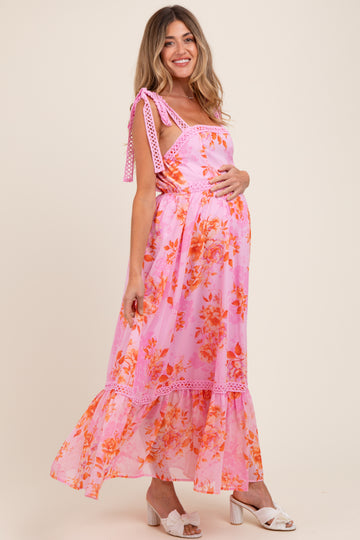 woman wearing a pink floral maternity maxi dress with tie straps and a visible baby bump