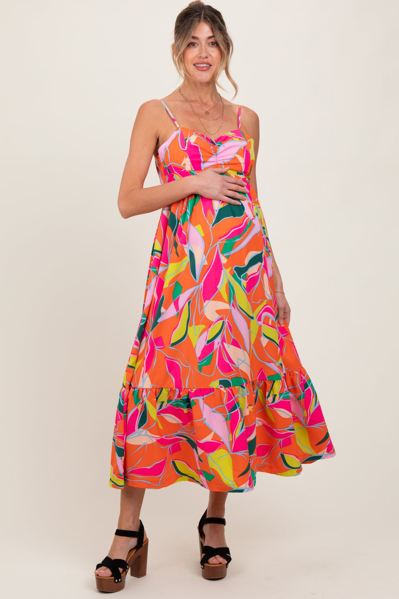 woman wearing a colorful floral maternity maxi dress and holding her baby bump