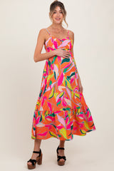 woman wearing a colorful floral maternity maxi dress and holding her baby bump