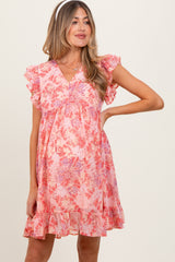 woman wearing a pink floral maternity dress with flutter sleeves and a ruffle hem, showcasing a baby bump