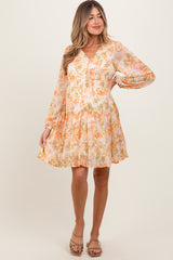 woman wearing a cream floral maternity dress with long sleeves and a V-neckline, holding her baby bump