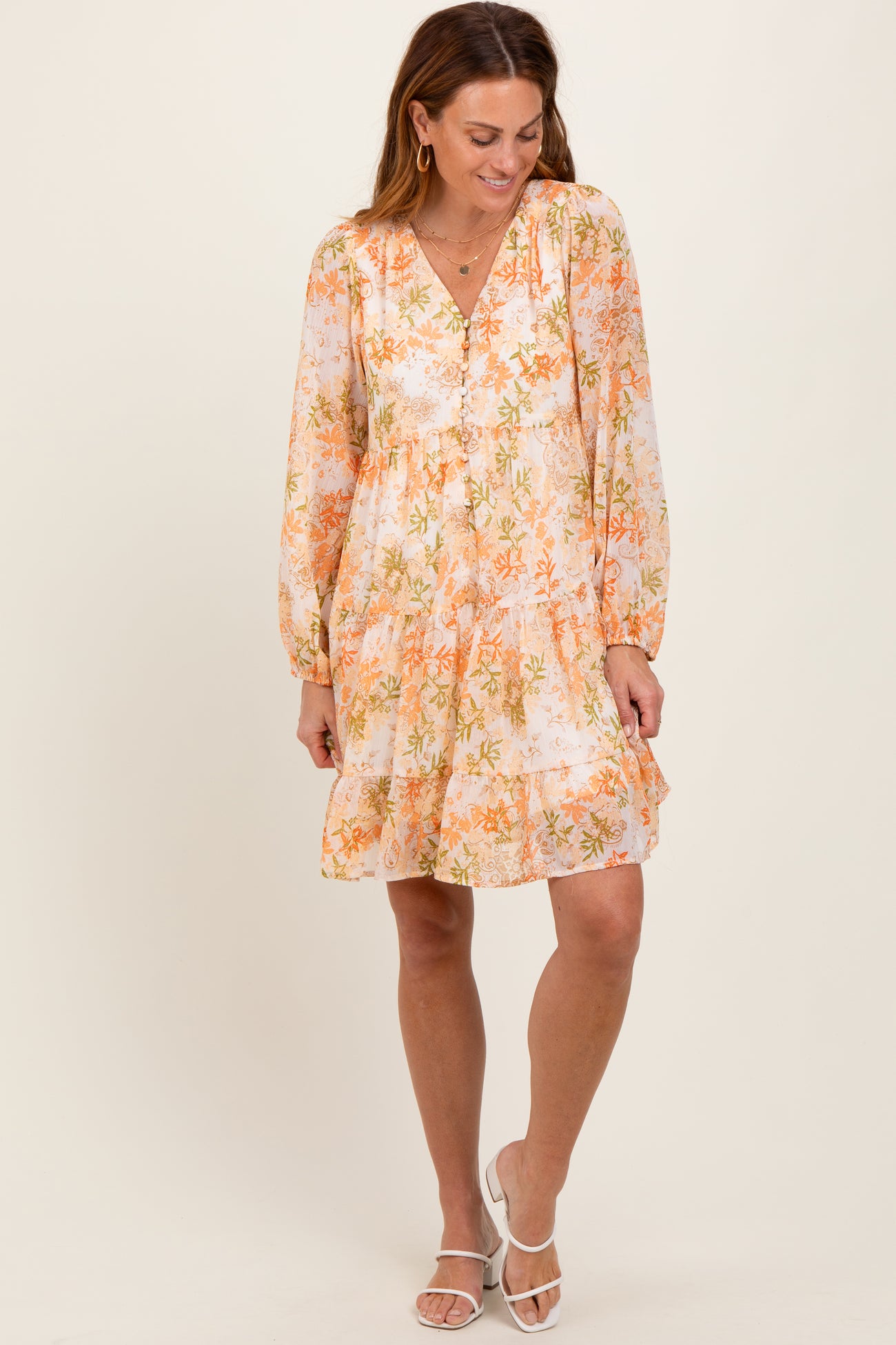 woman wearing an orange and white floral long sleeve dress with a V-neckline and tiered ruffle hem