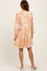 woman wearing a floral long sleeve mini dress in pastel colors with a tiered skirt and a relaxed fit
